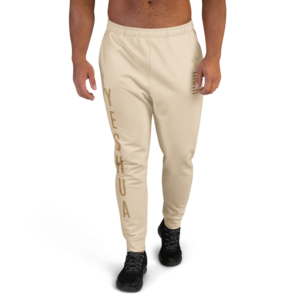 Beige sweatpants with 'Yeshua' text worn by a person on a white background